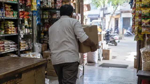 A man carrying a cardboard carton through the doorway of a shop